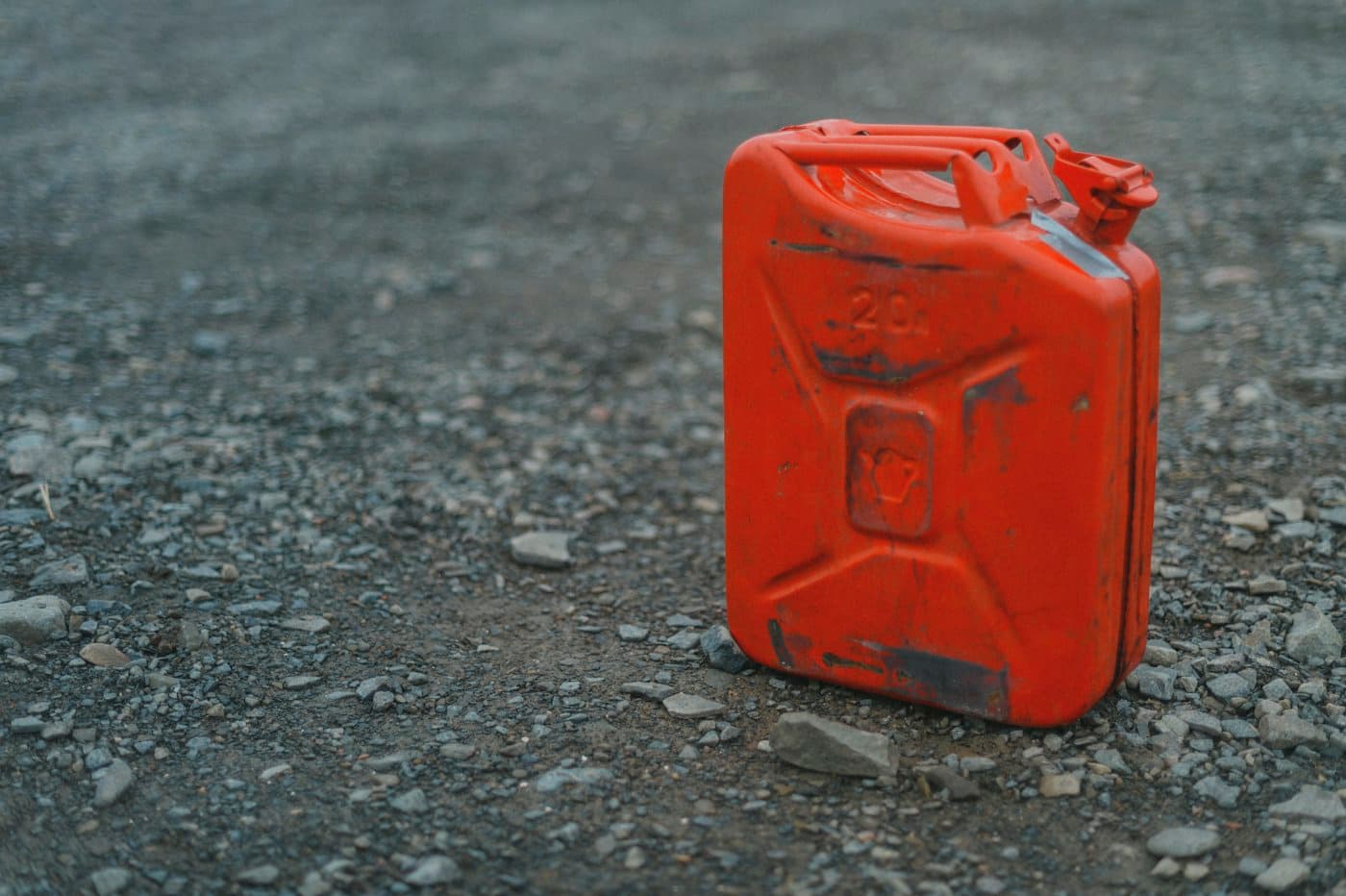 Red fuel canister on a gravel road shoulder