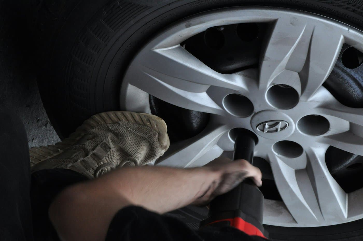 Technician using an impact wrench on a car wheel